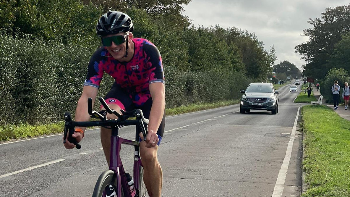 Man riding a bike with a smile on his face during an ironman triathlon
