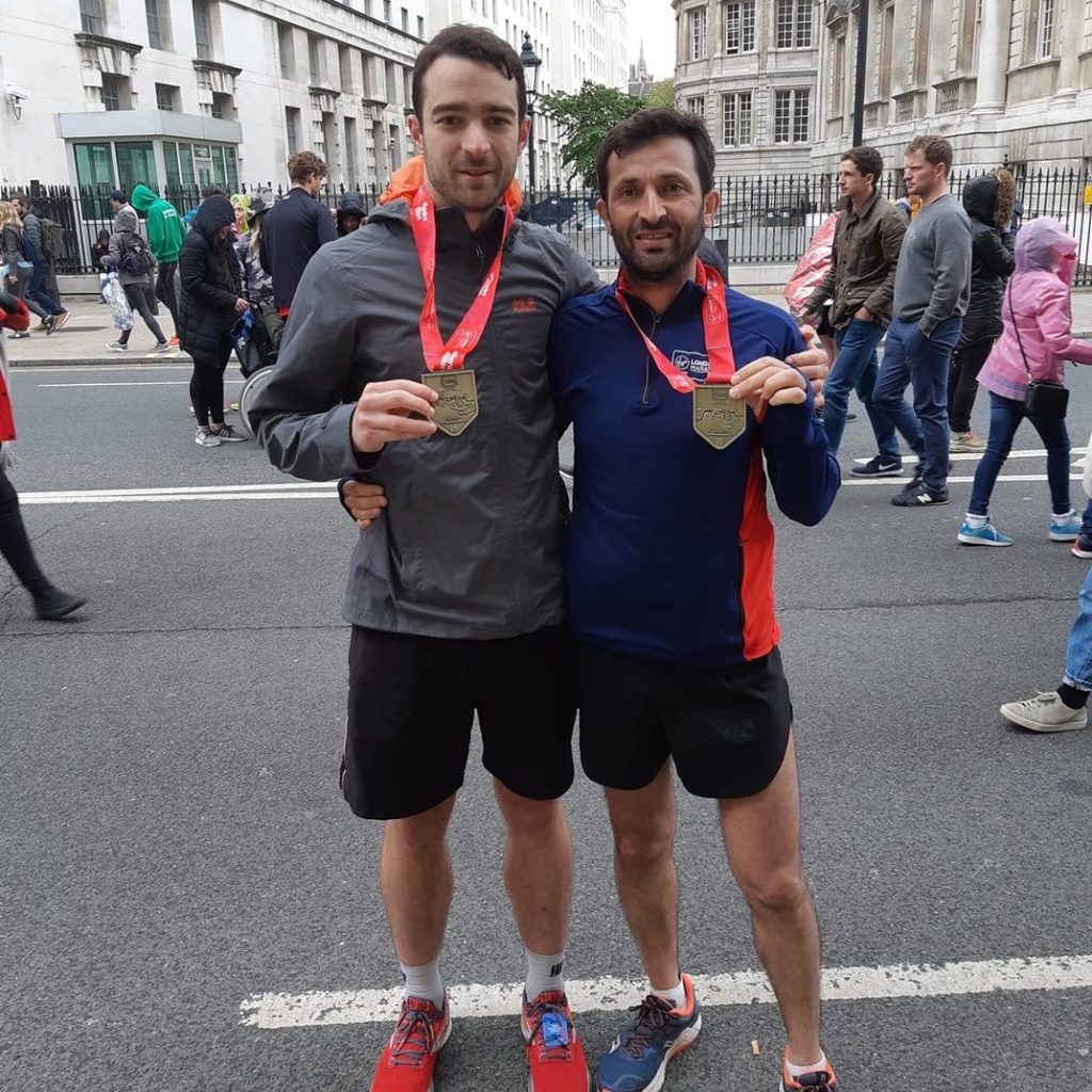 2 Runners smiling and holding out their london marathon 2019 medals