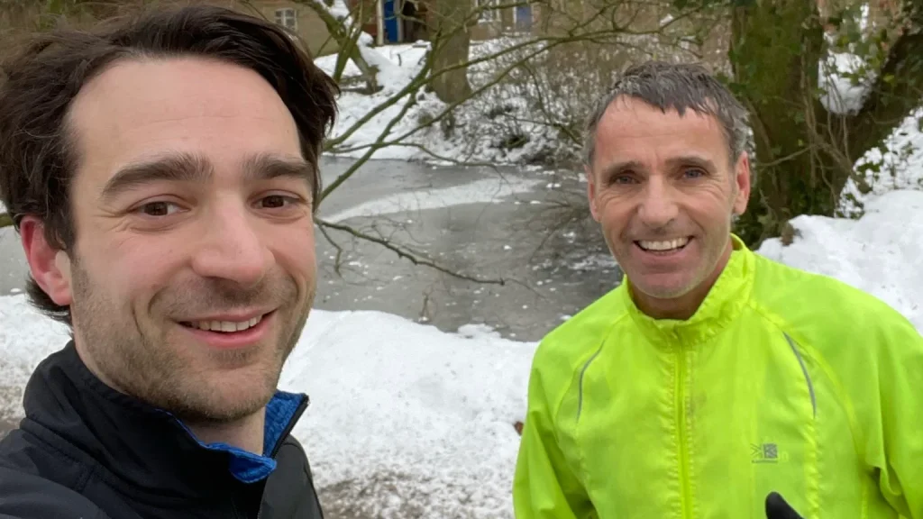 2 Runners smiling with snow in the background