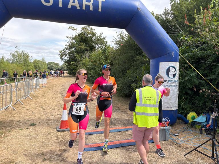 3 triathletes in bright colours cross the finish line together